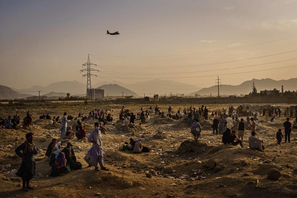 2021年8月23日，阿富汗首都喀布爾，沒有趕及登上美軍軍機的阿富汗人民在機場外聚集，遠處有一輛美軍軍機起飛。