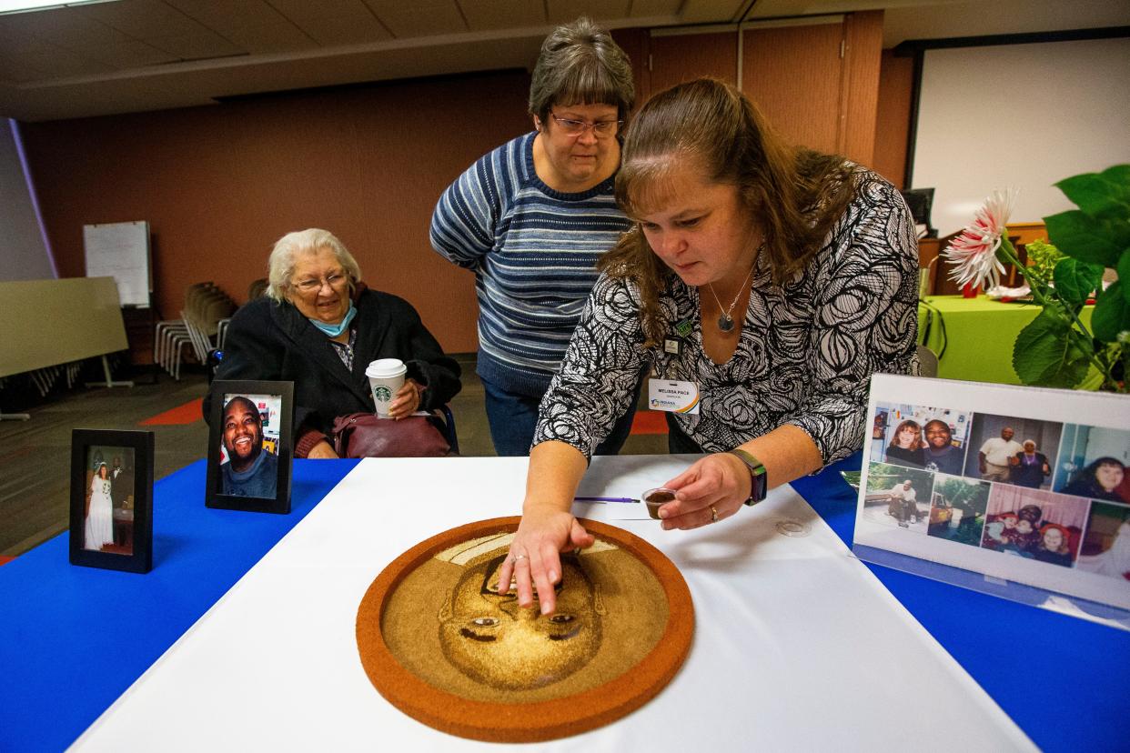 Melissa Pace, right, alongside her sister Lisa Batiz, center, and mother Dorothy Baitz, put the finishing touches on the portrait of Melissa's late husband Levell Pace that will be on a float at the Rose Parade during a Donate Life event Monday, Nov. 29, 2021 at IUSB. 