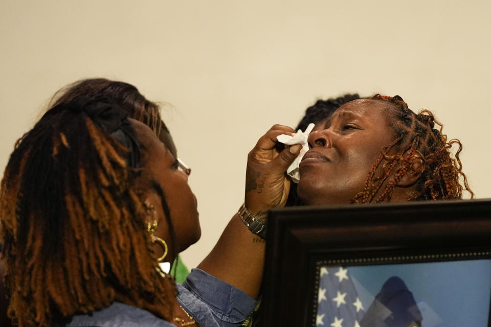 CORRECTS SERVICE BRANCH TO U.S. AIR FORCE INSTEAD OF U.S. NAVY - Family members wipe away the tears of Chantemekki Fortson, mother of Roger Fortson, a U.S. Air Force senior airman, as she holds a photo of her son during a news conference regarding his death, with attorney Ben Crump, Thursday, May 9, 2024, in Fort Walton Beach, Fla. Fortson was shot and killed by police in his apartment, May 3, 2024. (AP Photo/Gerald Herbert)