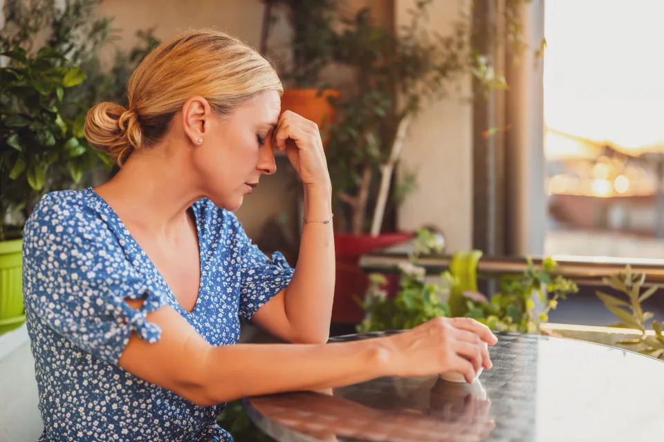 Donna a un tavolo sembra stressata o contemplativa, circondata da piante