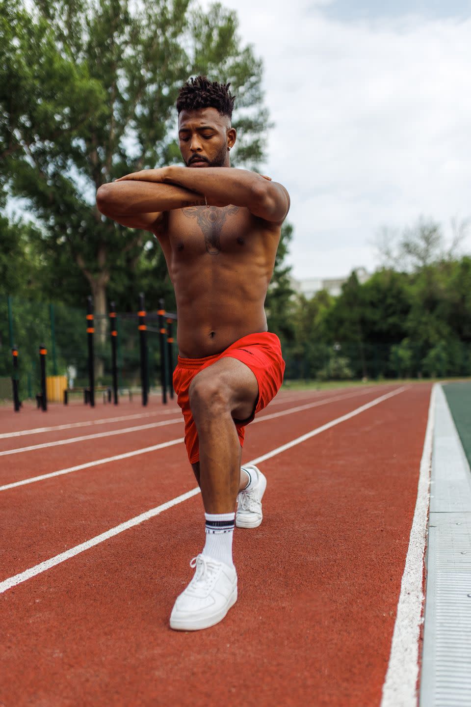 low angle view of nice young man of iranian ethnicity with afro hair doing bodyweight walking lunges outdoors