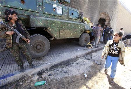 A boy walks alongside an armoured vehicles outside the central prison in Sanaa after a bomb exploded outside its main wall, February 14, 2014. REUTERS/Mohamed al-Sayaghi