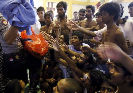 An Indonesia policeman distributes used clothes to migrants believed to be Rohingya inside a shelter in Lhoksukon, Indonesia's Aceh Province May 11, 2015. REUTERS/Roni Bintang
