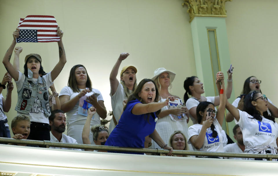 Opponents of recently passed legislation to tighten the rules on giving exemptions for vaccinations, demonstrate in the Assembly gallery after lawmakers approved the companion bill, at the Capitol in Sacramento, Calif., Monday, Sept. 9, 2019. The companion measure contained changes demanded by Gov Gavin Newsom as a condition of signing the controversial vaccine bill SB276 which was passed by the Legislature last week.(AP Photo/Rich Pedroncelli)