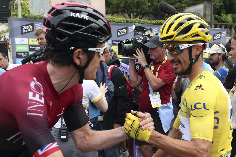 France's Julian Alaphilippe wearing the overall leader's yellow jersey shakes hands with Britain's Geraint Thomas as they arrive at the start of the fifteenth stage of the Tour de France cycling race over 185 kilometers (114,95 miles) with start in Limoux and finish in Prat d'Albis, France, Sunday, July 21, 2019. (AP Photo/Thibault Camus)