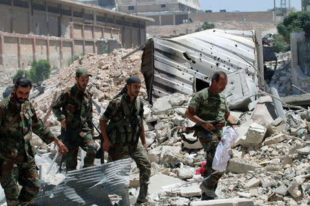 Forces loyal to Syria's President Bashar al-Assad walk with their weapons past rubble after they advanced on the southern side of the Castello road in Aleppo, Syria, in this handout picture provided by SANA on July 28, 2016. SANA/Handout via REUTERS