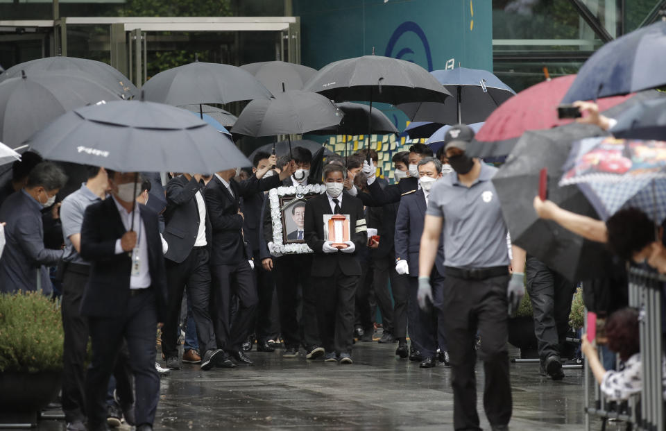 A man, holding a portrait of late Seoul Mayor Park Won-soon, leads a group of mourners as they leave the Seoul City Hall after his official funeral in Seoul, South Korea, Monday, July 13, 2020. Masked mourners gave speeches and laid flowers before the coffin of Seoul's mayor during his funeral Monday, while a live broadcast online drew a mixture of condolence messages and insults.(AP Photo/Lee Jin-man)