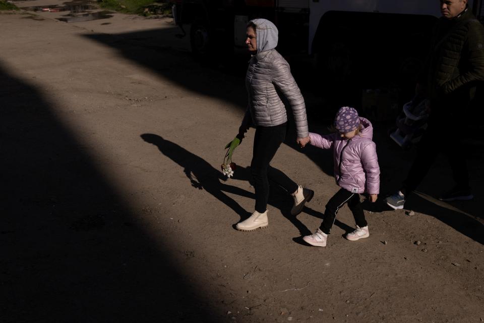 A woman with child holds flowers as she pays respect to civilians killed yesterday by a Russian missile strik (REUTERS)