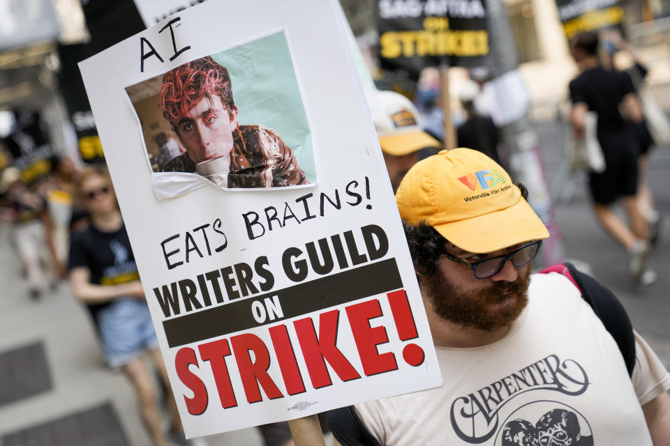 A signed disparaging artificial intelligence technology is carrier while striking writers and actors walk a picket line, Monday, July 17, 2023, in New York. Three years after the pandemic brought Hollywood to a standstill, the film and TV industry has again ground to a halt. This time, though, the industry is engaged in a bitter battle over the how streaming — after advancing rapidly during the pandemic — has upended the economics of entertainment. (AP Photo/John Minchillo)