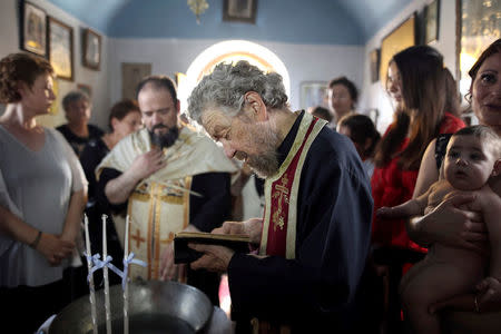 An Orthodox priest reads the gospel during the baptism of the first baby born on the islet of Thymaina after six years, with the financial support of the Aegean Team doctors, on the islet of Ayios Minas, Greece, May 12, 2017. REUTERS/Alkis Konstantinidis