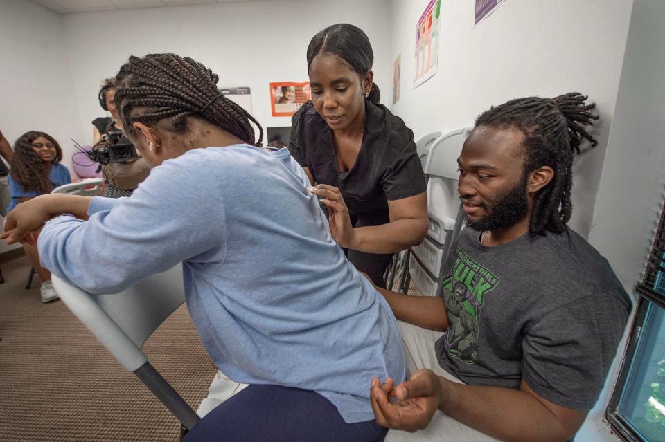 Doula Kashuna Walls, center, demonstrates a back massage technique to Aaron Bodie, 29, right, of Pearl, Miss., as he massages his wife Breanna Hill, 29, during a birthing class at Mom.ME in Flowood, Miss., Friday, April 21, 2023. Mom.ME is a nonprofit that supports, educates and advocates for mothers.