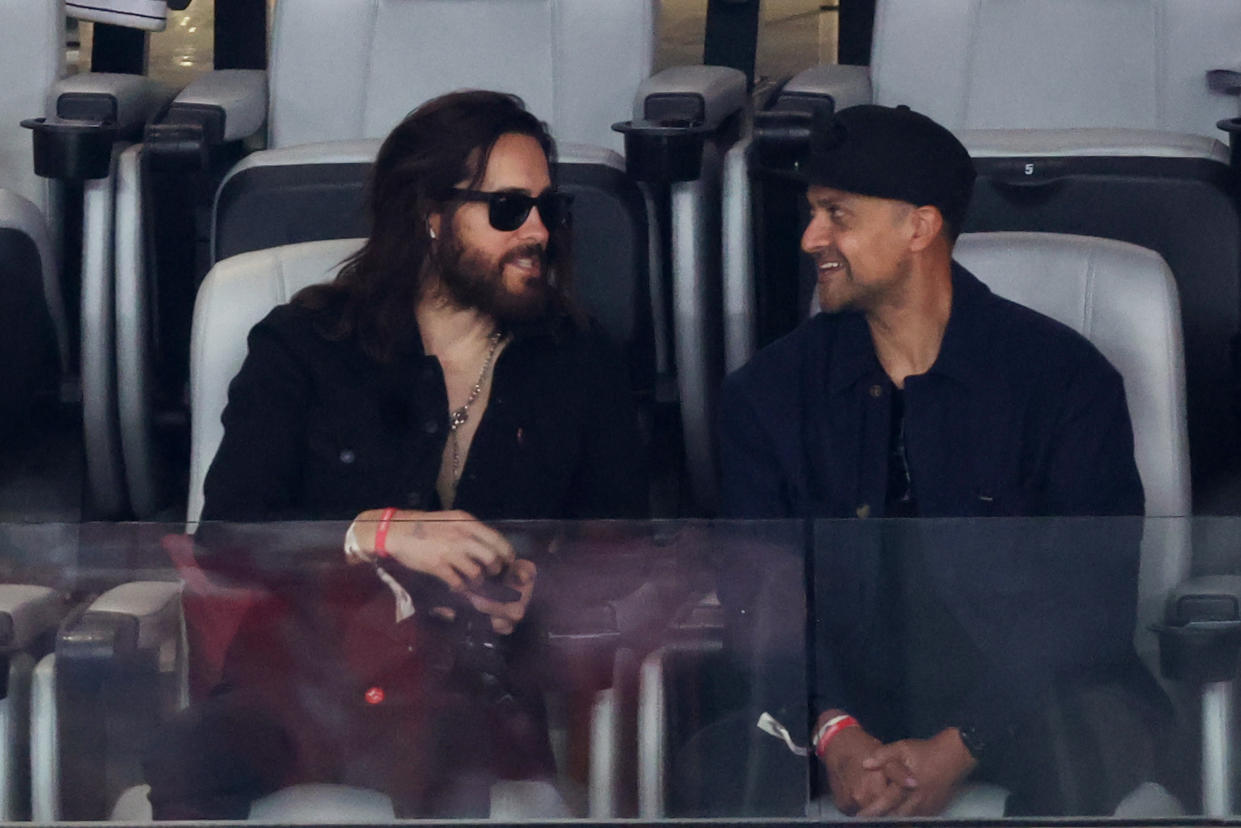 Actor Jared Leto, left, chats with someone in the seat next to him.
