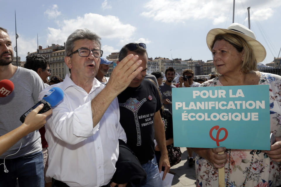 French far-left leader Jean-Luc Melenchon talks to the media during a demonstration for the climate, in Marseille, southern France, Saturday, Sept. 8, 2018. Demonstrators in cities across Europe are marching as part of a global day of protest ahead of a climate action summit later September in San Francisco, USA. Placard reads "For the environmental planning". (AP Photo/Claude Paris)