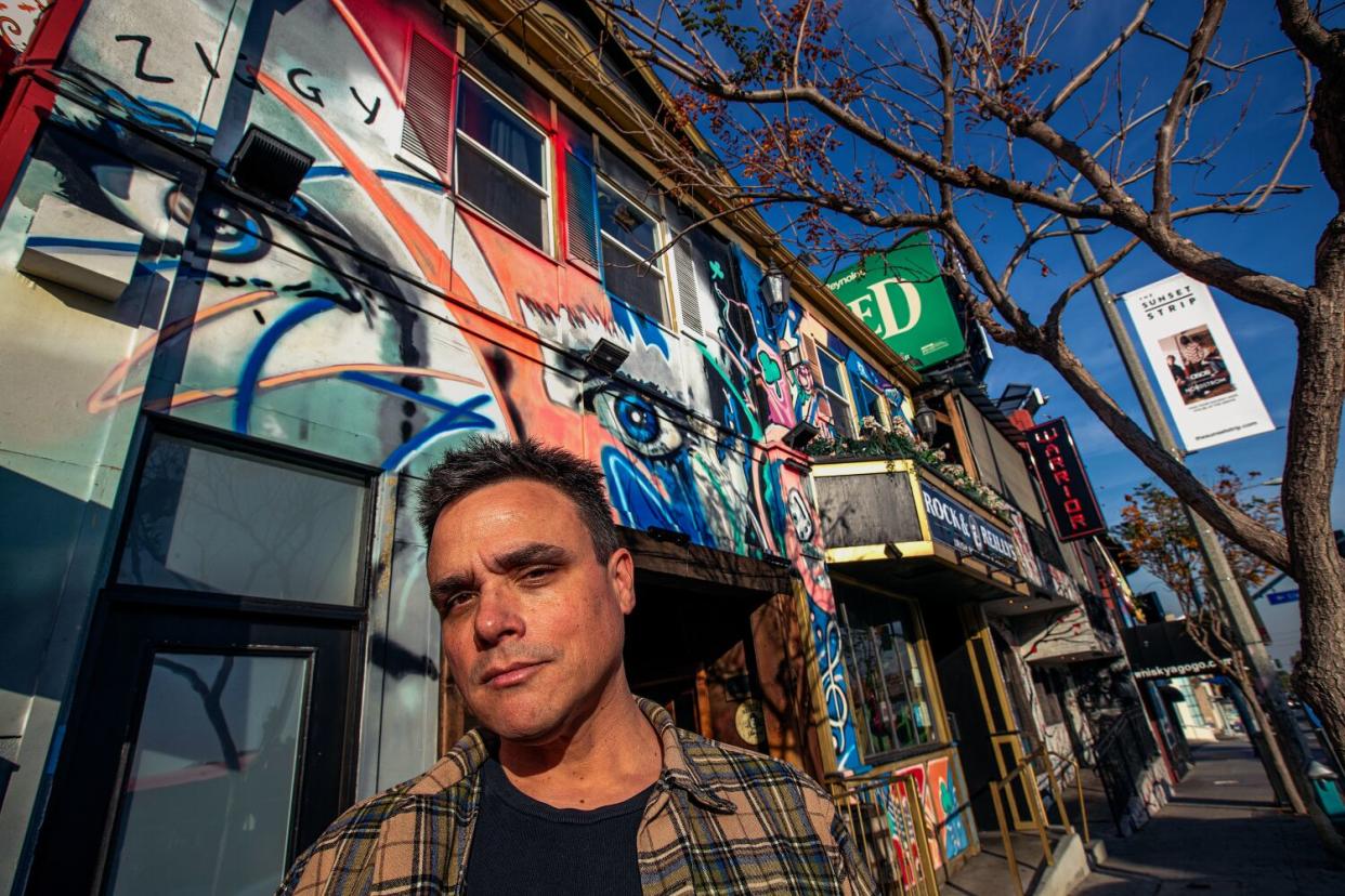 A man stands in front of a mural on the Sunset Strip.