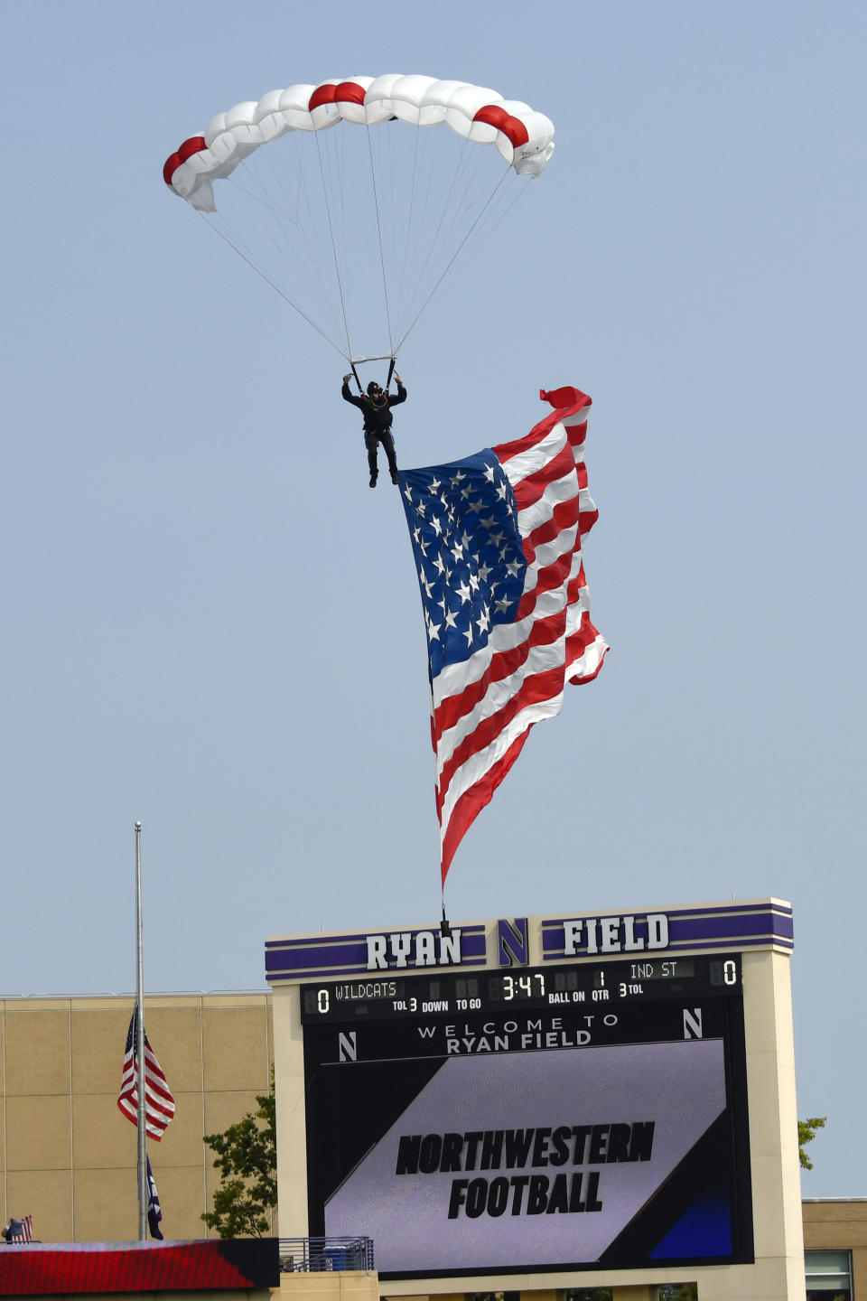 A sky diver lands on the field with an oversized United States flag prior to the start of an NCAA college football game between Northwestern and Indiana State in Evanston, Ill, Saturday, Sept. 11, 2021. (AP Photo/Matt Marton)