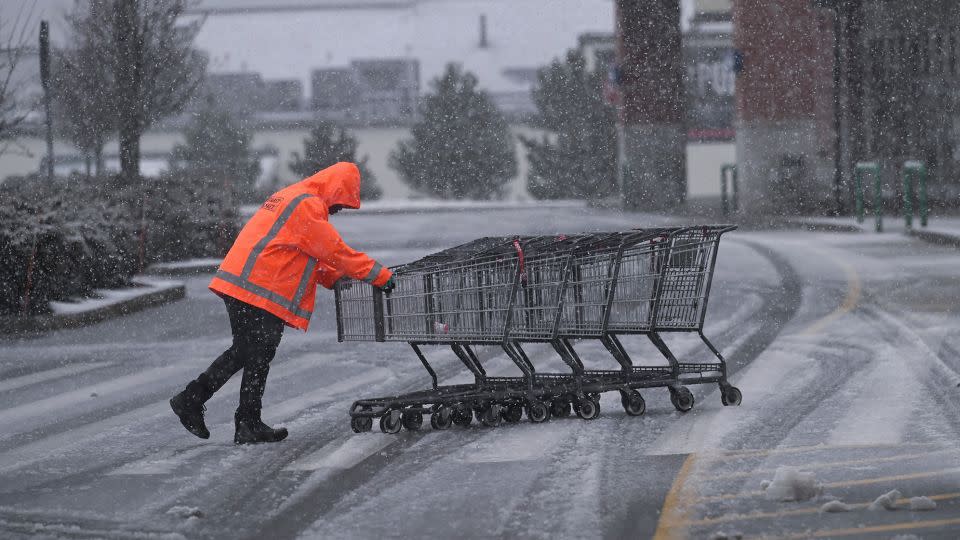 A supermarket employee returns shopping carts in the Market Basket parking lot in Plymouth, Massachusetts, during a fast-moving winter storm that hit the US Northeast February 13, 2024. - Ken McGagh/Reuters