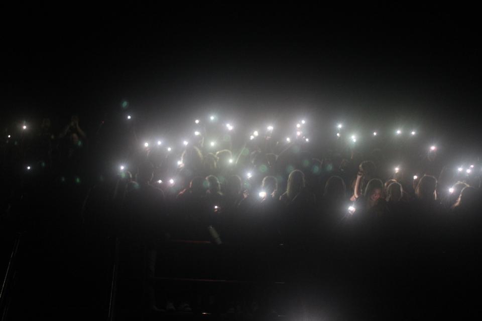 The Clinton student section shine their cell phones after the lights went out in the second quarter of Friday's game against Dundee.