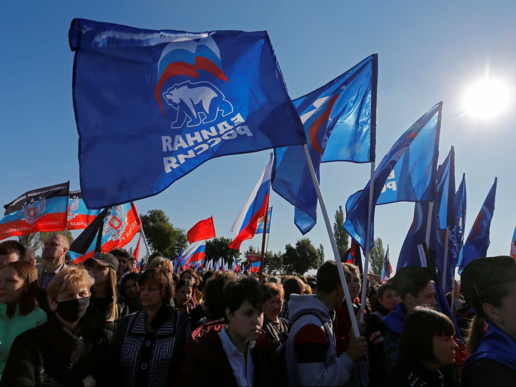 People hold flags of Russia’s ruling United Russia party, during a rally at the war memorial complex Savur-Mohyla (REUTERS)