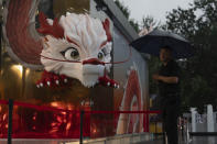 A security person stands in the rain near a depiction of a dragon at a shopping district in Beijing, July 30, 2024. (AP Photo/Ng Han Guan)