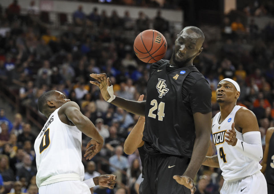 Central Florida's Tacko Fall (24) dodges a loose ball with VCU's De'Riante Jenkins and Corey Douglas (4) defending during the first half of a first-round game in the NCAA men’s college basketball tournament Friday, March 22, 2019, in Columbia, S.C. (AP Photo/Richard Shiro)