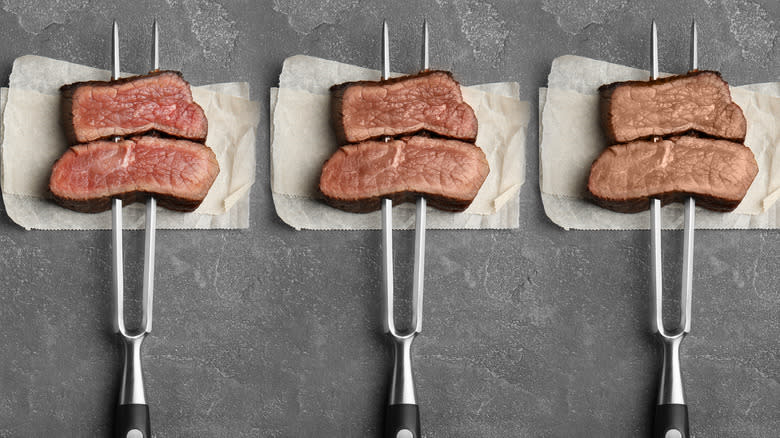 Forks with pieces of steak cooked to different degrees