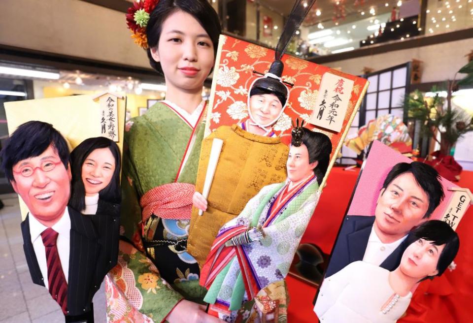 A Kyugetsu employee displays hagoita – ornamental wooden rackets – decorated with images of Shinjiro Koizumi and Christel Takigawa (R), Emperor Naruhito and Empress Masako (C) and Ryota Yamasato and Yu Aoi (L).