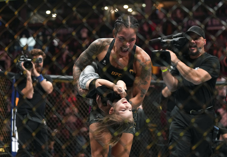 Amanda Nunes celebrates with her daughter after defeating Irene Aldana in a UFC 289 bout to hold on to her bantamweight title, in Vancouver, British Columbia, on Saturday, June 10, 2023. Nunes announced her retirement following the fight. (Darryl Dyck/The Canadian Press via AP)
