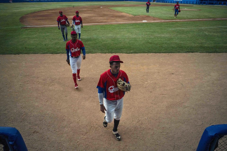 Several Cuban baseball players walk on the field during a break from the training session at the Estadio Latinoamericano in Havana, Cuba, Tuesday, May 18, 2021. A little over a week after the start of the Las Americas Baseball Pre-Olympic in Florida, the Cuban team does not have visas to travel to the United States. (AP Photo/Ramon Espinosa)