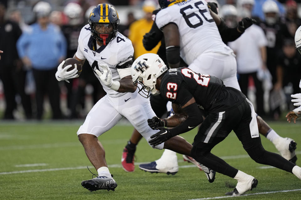 West Virginia running back CJ Donaldson Jr. (4) gets past Houston defensive back Isaiah Hamilton (23) on the way to a touchdown during the first quarter of an NCAA college football game Thursday, Oct. 12, 2023, in Houston. (AP Photo/Kevin M. Cox)