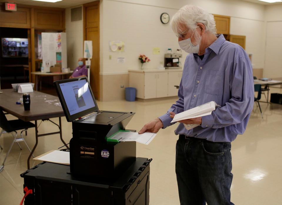 Poll worker Art deJong puts absentee ballots into the tabulator at First Congregational Church, Tuesday, April 6, 2021, in Sheboygan, Wis.