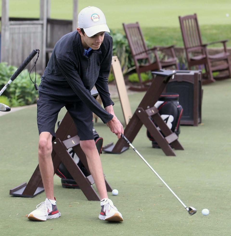 Huston Nagy, 16, of North Olmsted, hits the ball at the driving range at Firestone Country Club on Monday in Akron.