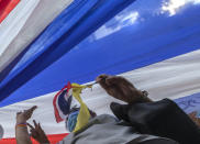 Supporter of Thailand's monarchy lift a giant national flag during a gathering stating their concern over the country's pro-democracy movement which they feel besmirches the royal institution in Bangkok, Thailand, Thursday, July 30, 2020. The demonstration was held at Democracy Monument, a traditional venue for protests of all political stripes that in recent weeks has hosted several larger pro-democracy, anti-government protests organized by students. (AP Photo/Sakchai Lalit)