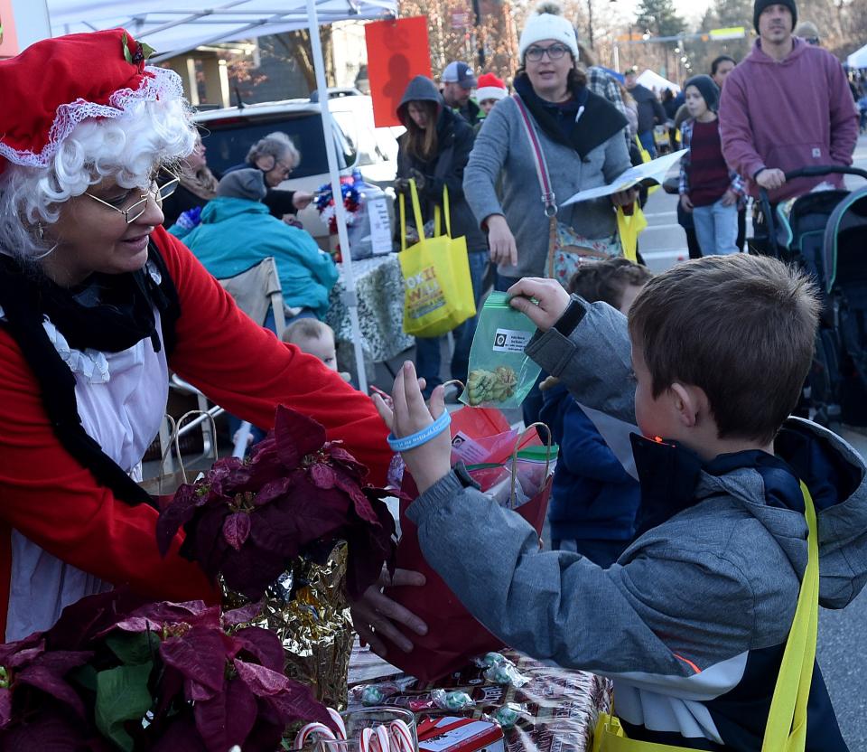 Anita Christie offers Sam Cronk, 7, a cookie while working the Watkins Memorial Band Booster's booth during Pataskala's annual Cookie Walk. Over 400 families walked the quarter mile route down Main Street in Pataskala picking up 23,000 cookies from 54 stops along the way.