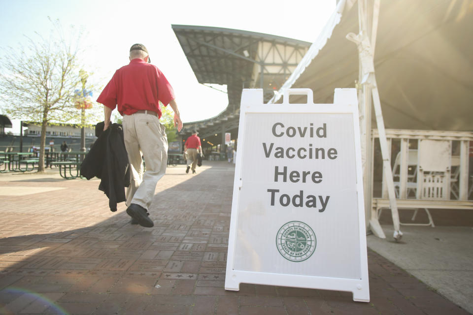 ROCHESTER, NEW YORK - MAY 18: Ballpark officials walk by a sign advertising free COVID-19 vaccines at before the game between the Rochester Red Wings and the Scranton/Wilkes-Barre RailRiders at Frontier Field on May 18, 2021 in Rochester, New York. (Photo by Joshua Bessex/Getty Images)