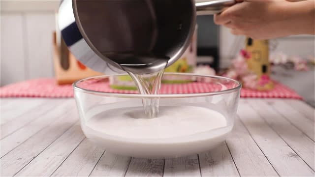 Pouring pandan sugar mixture into kueh lapis batter