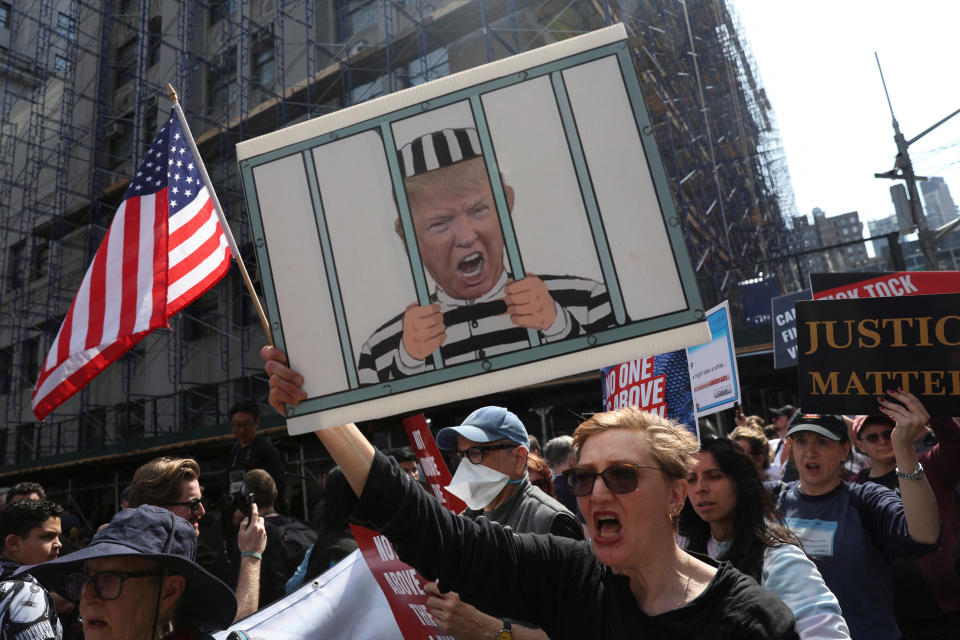 Demonstrators, one of whom holds a sign depicting Trump behind bars, rally outside Manhattan Criminal Courthouse.