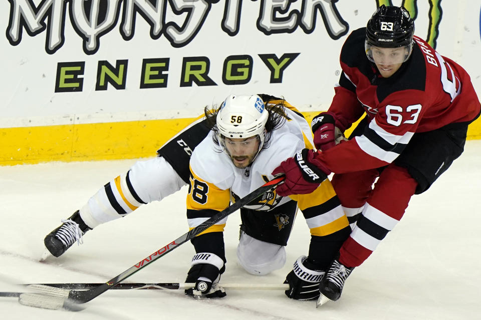 New Jersey Devils left wing Jesper Bratt (63) defends against Pittsburgh Penguins defenseman Kris Letang (58) during the first period of an NHL hockey game, Sunday, April 11, 2021, in Newark, N.J. (AP Photo/Kathy Willens)