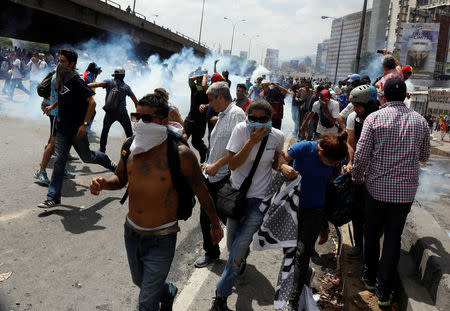 Demonstrators run from tear gas during an opposition rally in Caracas, Venezuela April 6, 2017. REUTERS/Carlos Garcia Rawlins