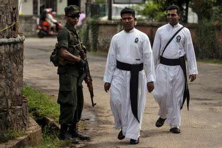 A soldier stands guard as priests walk past him outside St. Sebastian Church, days after a string of suicide bomb attacks across the island on Easter Sunday, in Negombo, Sri Lanka, May 1, 2019. REUTERS/Danish Siddiqui