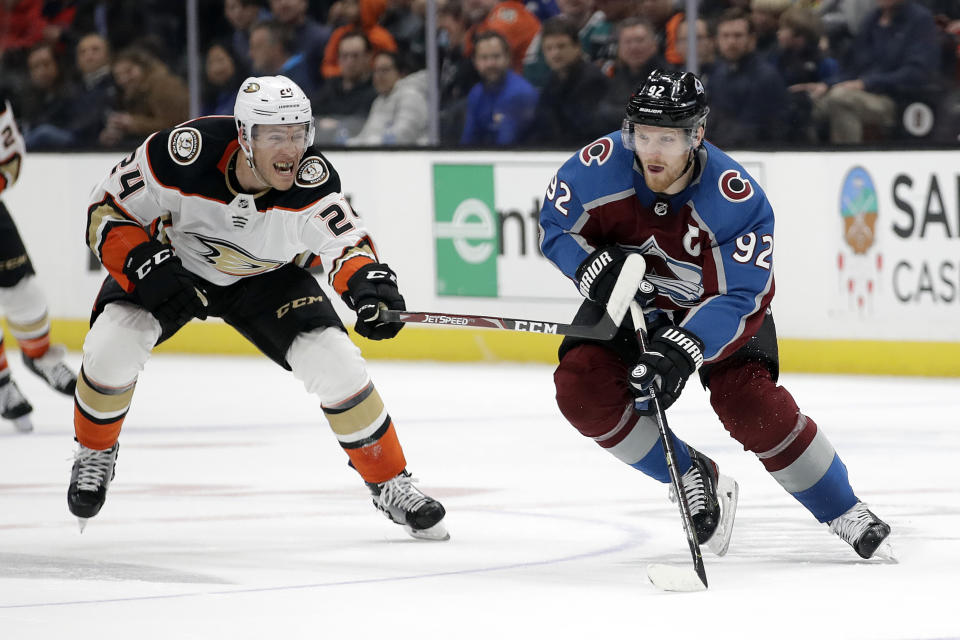 Colorado Avalanche's Gabriel Landeskog, right, is defended by Anaheim Ducks' Carter Rowney (24) during the first period of an NHL hockey game Friday, Feb. 21, 2020, in Anaheim, Calif. (AP Photo/Marcio Jose Sanchez)