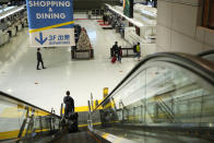 A woman goes down on an elevator to the departure ticketing counter floor at the Narita International Airport in Narita, east of Tokyo, Thursday, Dec. 2, 2021. Going further than many other countries in trying to contain the virus, Japan has banned foreign visitors and asked international airlines to stop taking new reservations for all flights arriving in the country until the end of December. (AP Photo/Hiro Komae)