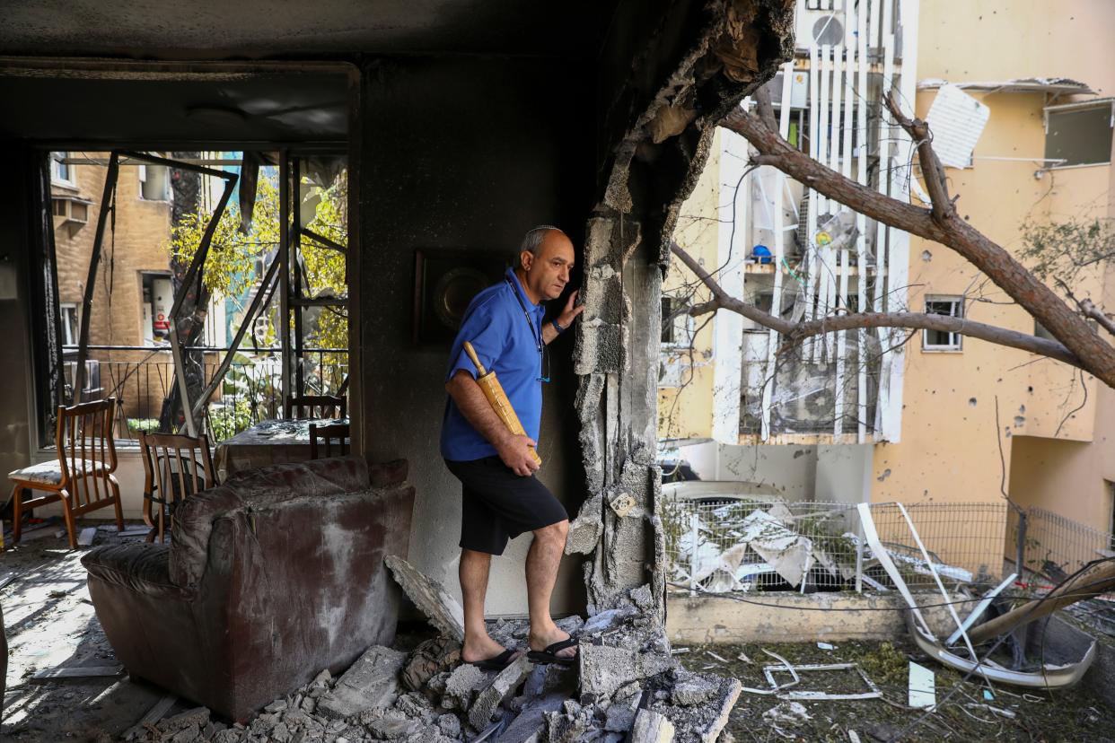 A family member inspects the damage of their apartment after being hit by a rocket fired from the Gaza Strip overnight in Petah Tikva, central Israel, Thursday, May 13, 2021.