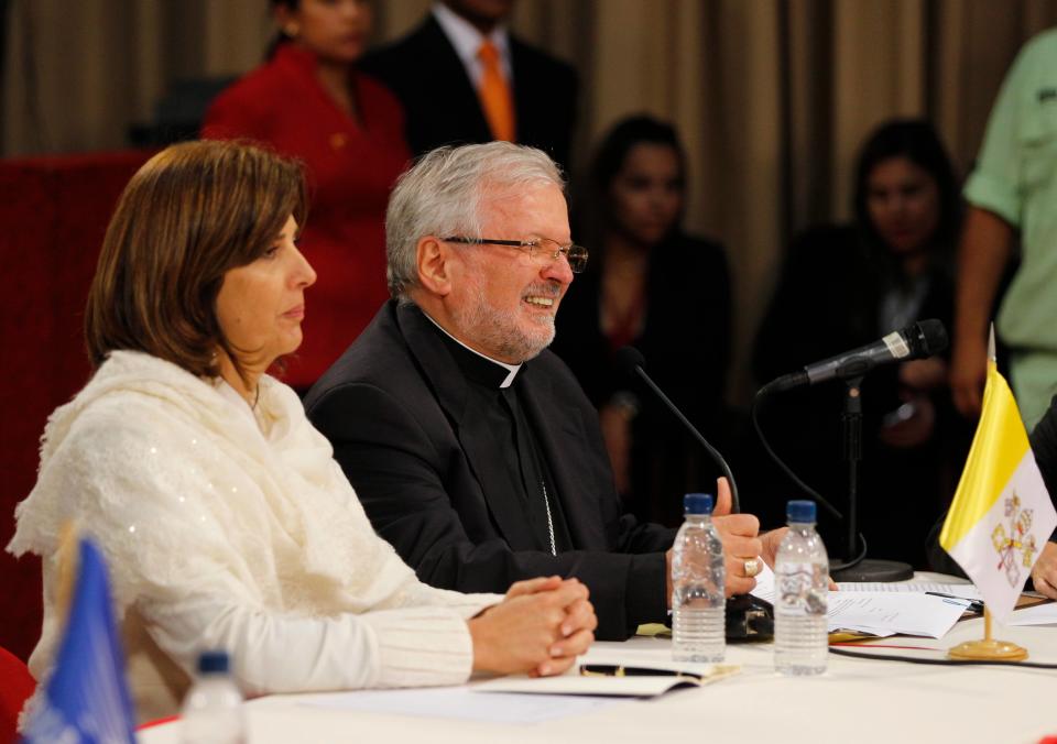 Aldo Giordano, Apostolic Nuncio to Venezuela, right, reads Pope Francis' written message at the start of a meeting between President Nicolas Maduro and key members of the opposition at Miraflores Presidential Palace in Caracas, Venezuela, Thursday, April 10, 2014. Pope Francis is urging Venezuela's government and its opponents to put aside their political differences and demonstrate the necessary courage to reach an agreement that ends weeks of violent protests. The Vatican is sponsoring the first talks aimed at reconciliation since protests began in early February. Colombia's Foreign Minister Maria Angela Holguin sits at left. (AP Photo/Fernando Llano)