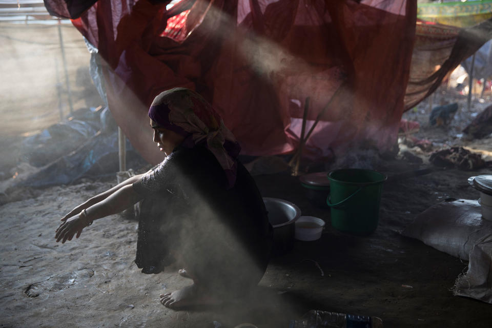 <p>Sajida Begum, 18, sits in her makeshift tent washing rice for dinner as smoke catches the late afternoon light on September 25, in Thainkhali camp, Cox’s Bazar, Bangladesh. (Photograph by Paula Bronstein/Getty Images) </p>