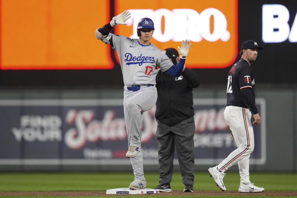 Los Angeles Dodgers two-way player Shohei Ohtani (17) gestures toward the dugout after hitting a double during the sixth inning of a baseball game against the Minnesota Twins, Monday, April 8, 2024, in Minneapolis. (AP Photo/Abbie Parr)