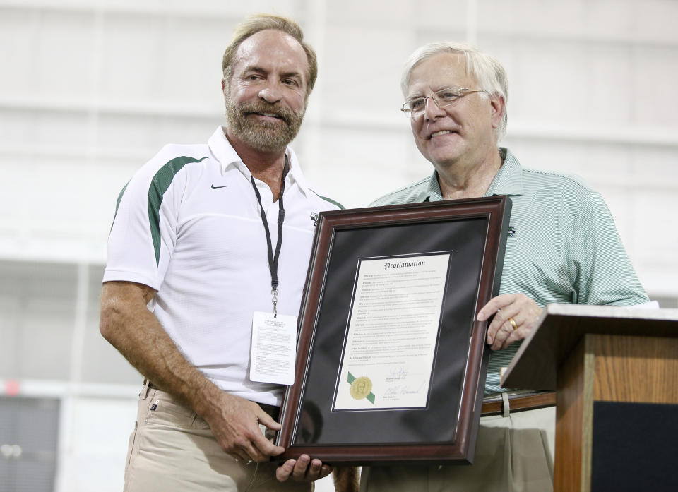 In this Sept. 6, 2014 photo, President Stephen Kopp, right, congratulates Chris Cline as Marshall University dedicates the new indoor practice facility as the Chris Cline Athletic Complex in Huntington, W.Va. Police in the Bahamas say a helicopter flying from Big Grand Cay island to Fort Lauderdale has crashed, killing seven Americans on board. None of the bodies recovered from the downed helicopter have been identified, but police Supt. Shanta Knowles told The Associated Press on Friday, July 5, 2019, that the missing-aircraft report from Florida said billionaire Chris Cline was on board. (Sholten Singer/The Herald-Dispatch via AP)