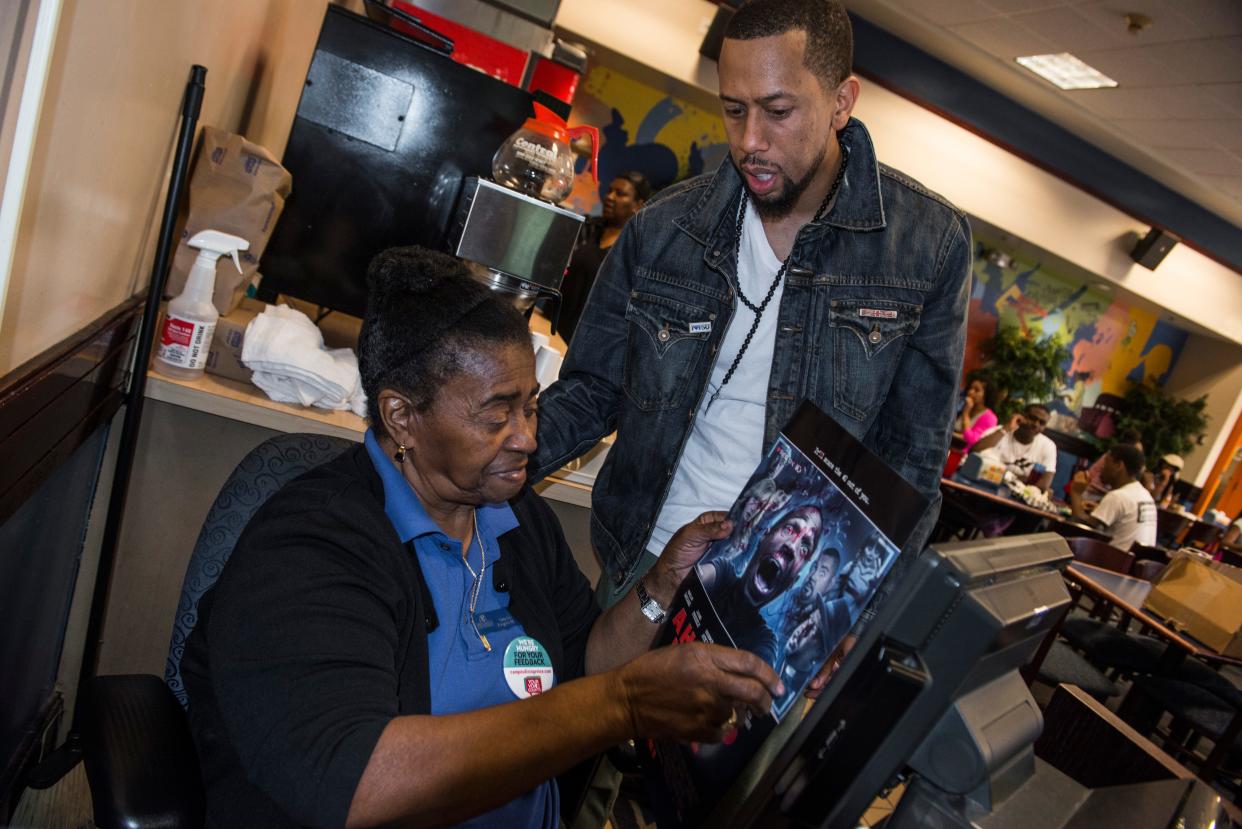 Affion Crockett gives Rodgriee Melvin an autograph poster, in April 2014 at the Fayetteville State University cafeteria.