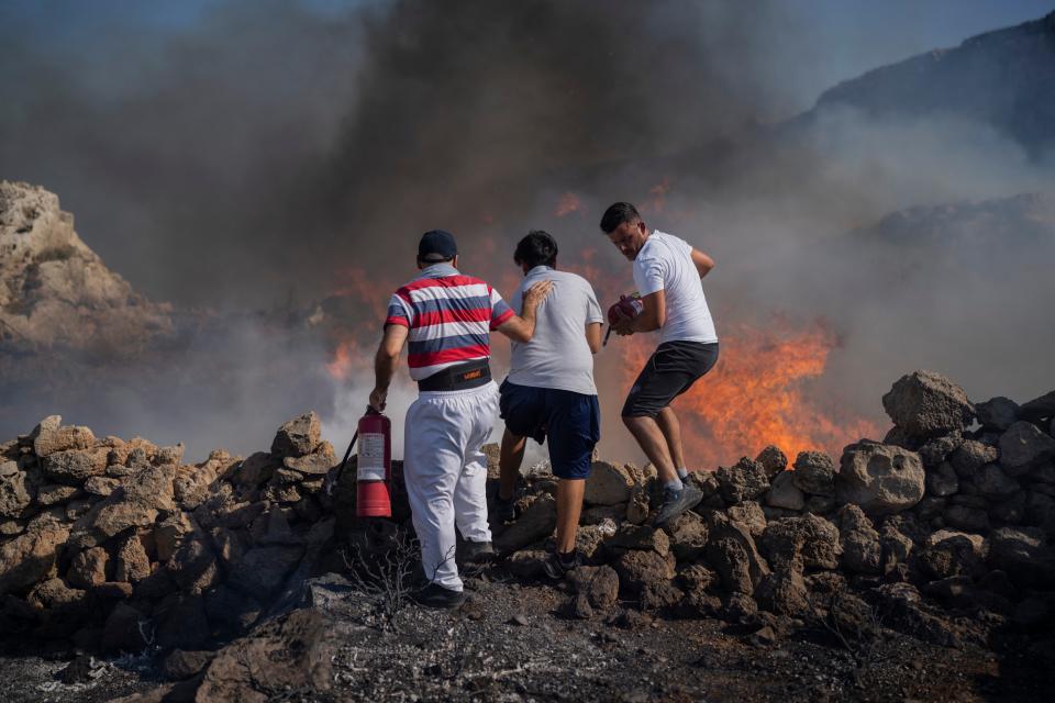 Local residents try to extinguish a fire, near the seaside resort of Lindos, on the Aegean Sea island of Rhodes, southeastern Greece (AP)