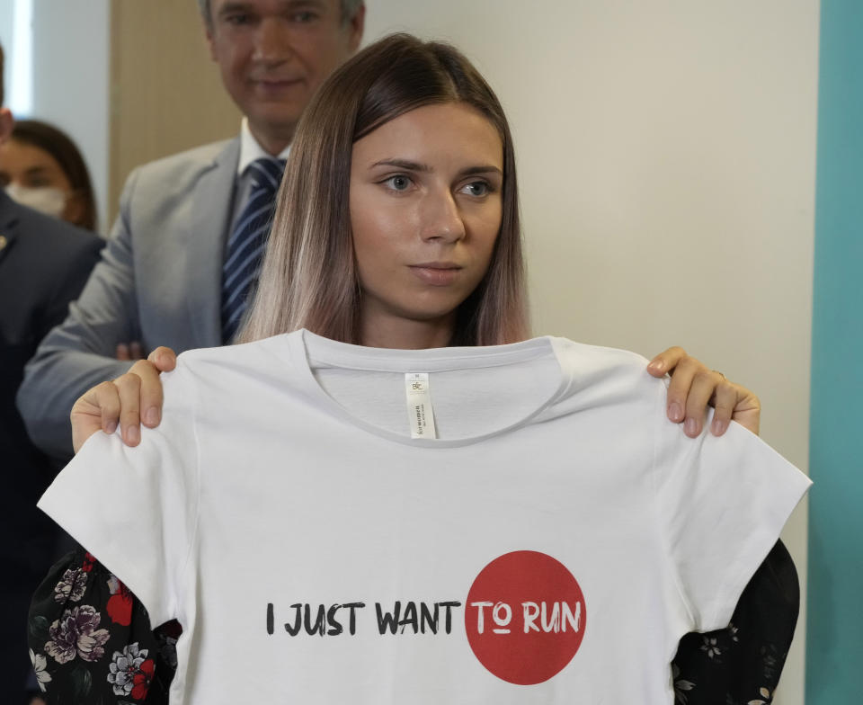 Belarusian Olympic sprinter Krystsina Tsimanouskaya, who came to Poland Wednesday fearing reprisals at home after criticizing her coaches at the Tokyo Games, is showing an Olympic-related T-shirt with her slogan "I Just Want to Run" after her news conference in Warsaw, Poland, on Thursday, Aug. 5, 2021. Tsimanouskaya reached Poland by plane from Tokyo through Vienna, a circuitous route due to security concerns, days after she accused team officials of trying to force her to fly back to Belarus, where an authoritarian government has relentlessly pursued its critics. (AP Photo/Czarek Sokolowski)