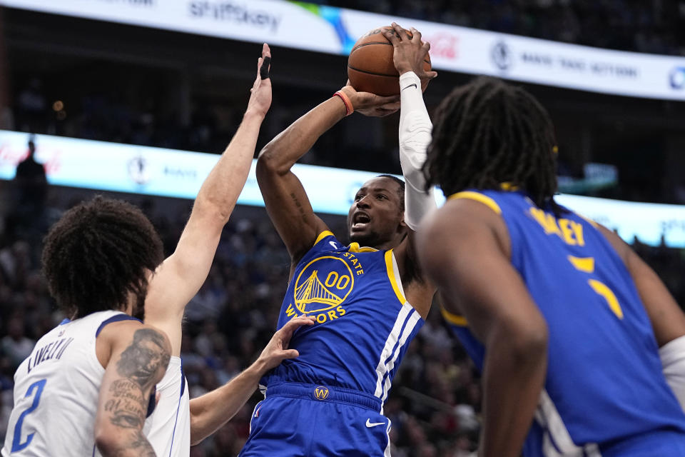 Golden State Warriors' Jonathan Kuminga (00) shoots as Dallas Mavericks' Dereck Lively II (2) and others defend during the first half of an NBA basketball game in Dallas, Wednesday, March 13, 2024. (AP Photo/Tony Gutierrez)